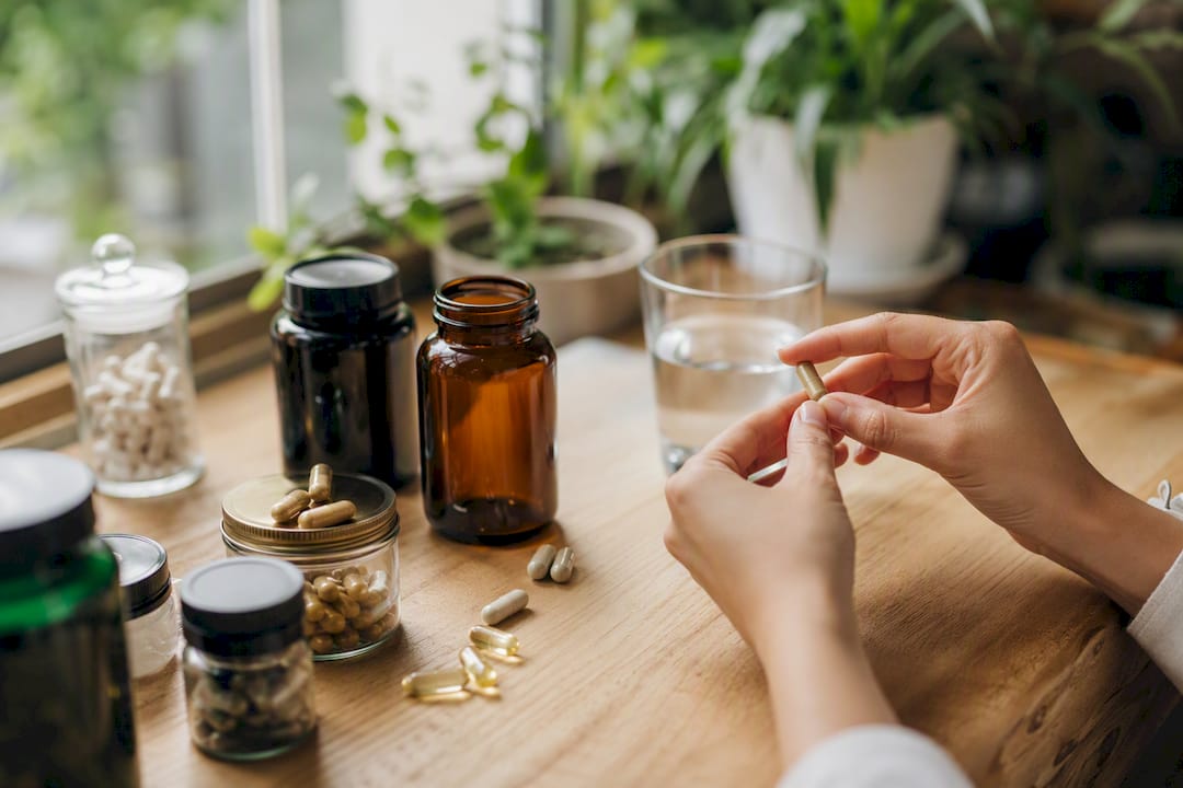Frasco de suplementos veganos y cápsulas sobre madera